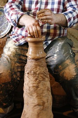hands who makes on a potter's wheel a jug made of clay