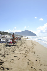 Relaxed people on the Sabaudia beach for the summer holidays. The Circeo Mountain on the background. Sabaudia, Lazio, Italy.