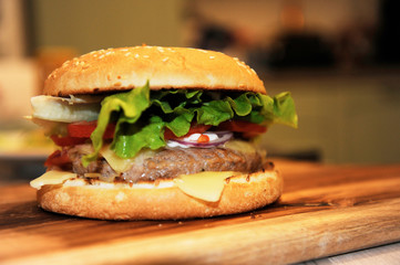 Closeup of home made beef burger with lettuce and mayonnaise served on little wooden cutting board.