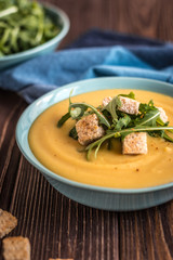 Pea soup with with croutons and greens on a wooden background. Pea cream soup.