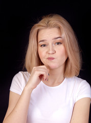Pensive portrait of a young woman in a white T-shirt on a black background