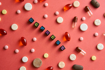 Multicolored title DEPRESS from black cubes on the table with tablets on coral background