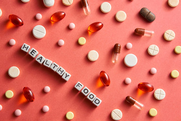 Black-and-white title HEALTHY FOOD from white cubes on the table with tablets on coral background