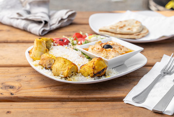 Greek chicken platter with rice and hummus served in a Mediterranean restaurant.