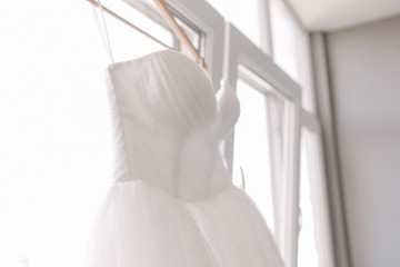 Elegance White Wedding Dress on Shoulders near Window. Close-up of Romantic Accessory of Happy Bride Bright Interior Background. Beautiful Special Symbol of Happiness and Love Concept