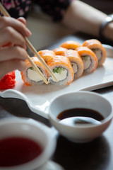 Girl eats sushi and rolls with chopsticks in a restaurant