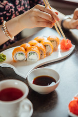 Girl eats sushi and rolls with chopsticks in a restaurant