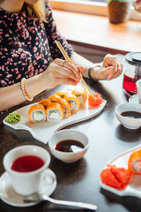 Girl eats sushi and rolls with chopsticks in a restaurant