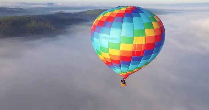 Colorful hot air balloon epic flying above mountain over the fog at sunrise