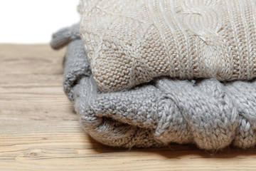 Pile of knitted winter clothes on wooden background, sweaters, knitwear, space for text