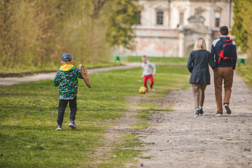 Obraz premium kids playing with ball and wooden shield parents walking by alley