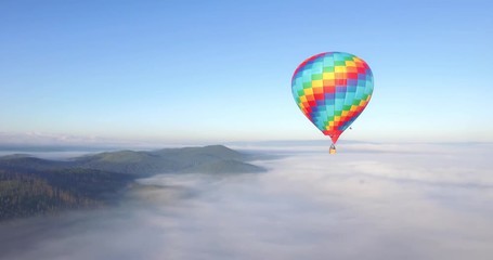 Colorful hot air balloon epic flying above mountain over the fog at sunrise