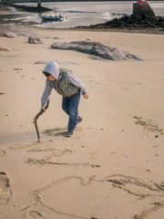 Child writing a message on the sand, hopin it will be seeing from up above