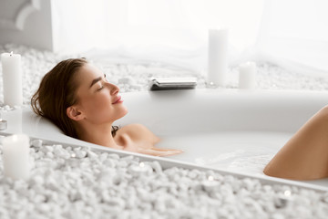 Beautiful Woman Relaxing In Milky Bathtub With Closed Eyes