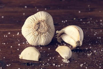 garlic cloves and spices in pieces on a wooden cutting board