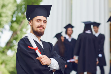A young male graduate against the background of university graduates.