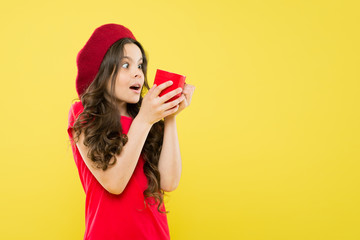 happy girl with long curly hair in beret. childhood. hairdresser salon. parisian child on yellow backdrop. beauty and fashion. little girl in french style hat. Tea time. lifestyle concept. copy space