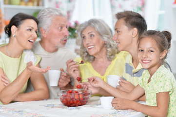 Portrait of big happy family eating fresh strawberries at kitchen
