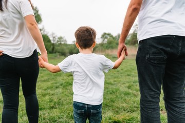 Fototapeta premium Happy family: mother father and child son on nature on sunset. Mom, Dad and kid laughing and hugging, enjoying nature outside. Sunny day, good mood. concept of a happy family