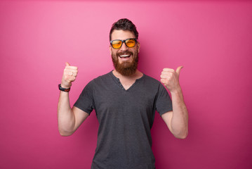 I like it!! Bearded man doing like geasture with thumbs up, isolated pink background