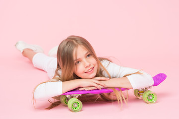 Obraz na płótnie Canvas Trendy girl. Girl likes to ride skateboard. Active lifestyle. Girl having fun with penny board pink background. Kid adorable child long hair adore ride penny board. Ride penny board and do tricks