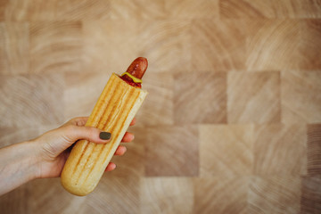 close up of woman hands with hot dog on wall background. fast food, people and unhealthy eating concept