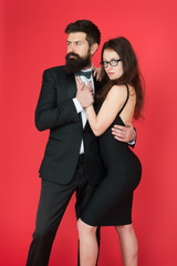 Couple man in tuxedo and elegant girl. Man bearded hipster and woman in formal dress red background. Formal fashion and elegant clothes. Luxury fashion boutique. Fashion clothes shop. Official event