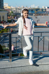 Obraz premium Exciting journeys through cities and museums. City guide and audio tour. Girl little tourist kid using audio guide mobile application. Audio tour headphones gadget. Free style of travelling