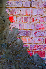 Old red brick wall half covered with cement plaster