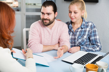 Obraz premium Young family and mother with documents sitting at table in home interior