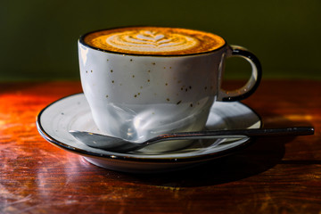 Coffee cup with cappuccino on the worn polished tabletop