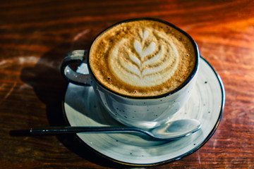 Coffee cup with cappuccino on the worn polished tabletop above view