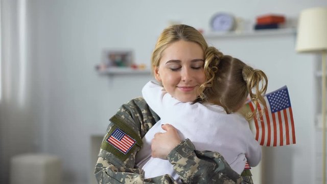 Joyful american soldier woman hugging little sister with national flag, patriot