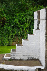 Side view of concrete stairs painted in white. Trees are seen in the background.