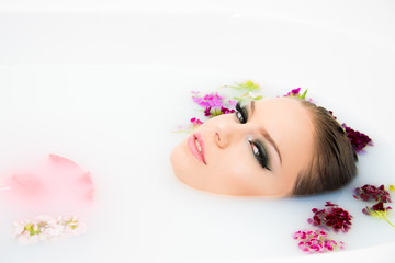 Obraz na płótnie Canvas beautiful model woman face make up close up in milk bath beauty care and spa concept with flowers