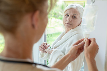 Doctor and sick elder patient during chemotherapy at home. Home cancer treatment concept