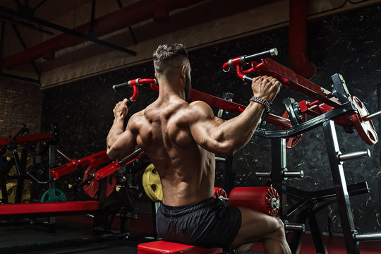 Young handsome sportsman bodybuilder weightlifter with an ideal body, after coaching poses in front of the camera, abdominal muscles, biceps triceps. In sportswear.
