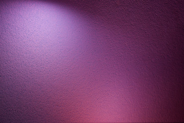 On a purple textural background, a light violet ray of light and a pink spot of light
