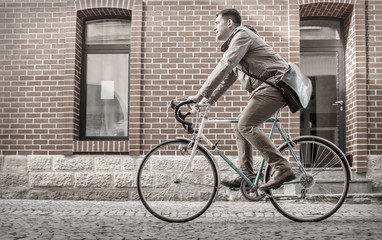 Fototapeta premium Young stylish businessmango to work on his sport retro bike in s