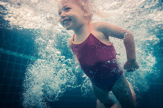 Happy child toddler swimming underwater in swimming pool