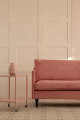Pastel pink couch in white living room interior, copy space on empty wall