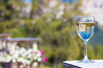 Glass of chilled white wine on a rocky mountain background. Hiking in Dolomites, Italy