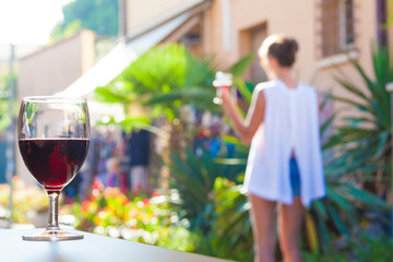 glass of red wine on table over young woman and Bardolino backgound