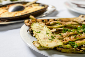 Close up on zucchini courgette Summer squash salad with garlic and oil on a white plate on the table