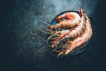 Giant Raw fresh Tiger Prawns in the plate over stone background, top view