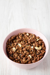 Homemade chocolate granola with nuts in a pink bowl, low angle view. Copy space.