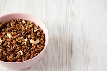 Homemade chocolate granola with nuts in a pink bowl, low angle view. Space for text.