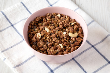 Homemade chocolate granola with nuts in a pink bowl, low angle view.