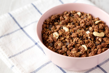Homemade chocolate granola with nuts in a pink bowl, side view. Closeup.