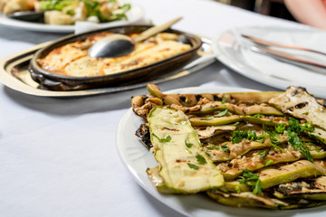 Close up on zucchini courgette Summer squash salad with garlic and oil on a white plate on the table